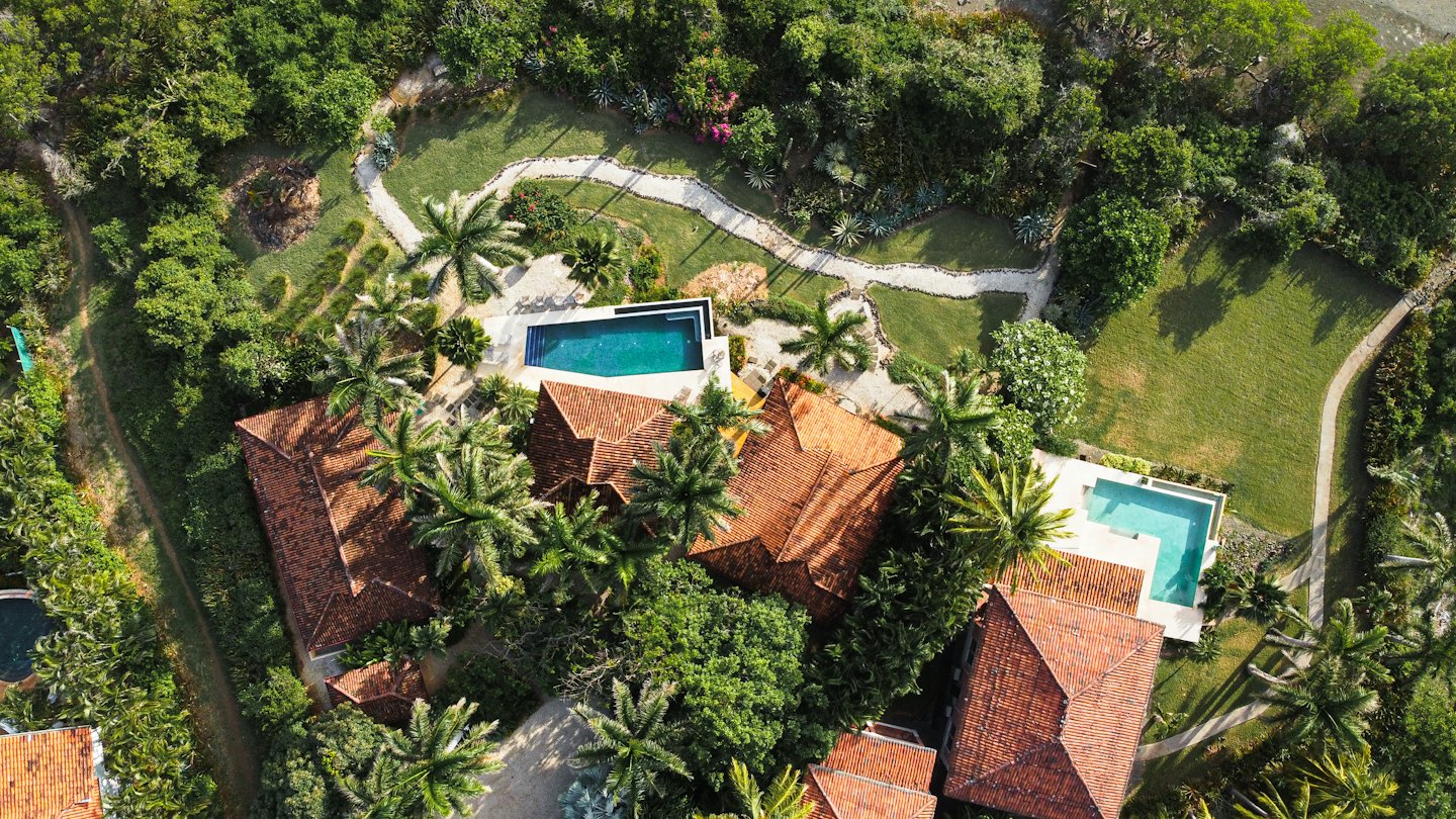Tropical estate buildings with terracotta roofs surrounded by lush greenery.