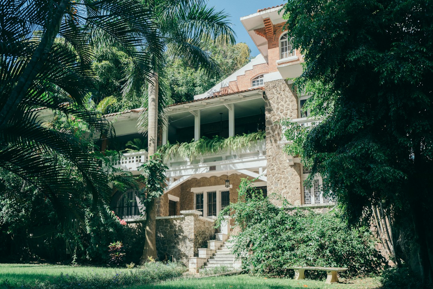 Grand stone house with red brick accents and ornate balconies.