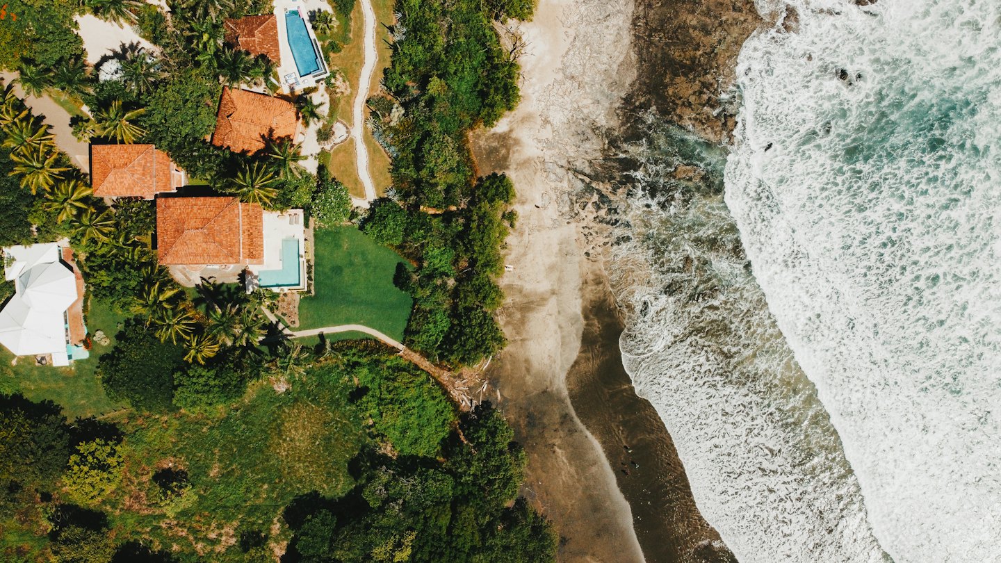Coastal villas with pools surrounded by tropical trees and sandy beaches.